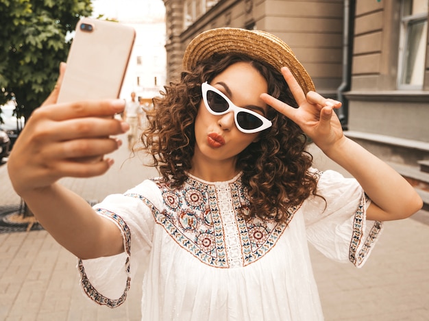 Hermosa modelo sonriente con peinado afro rizos vestido con vestido blanco hipster de verano.