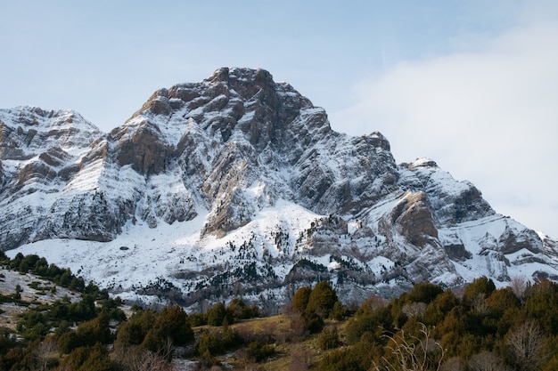 Hermosa montaña rocosa cubierta de nieve bajo un cielo nublado