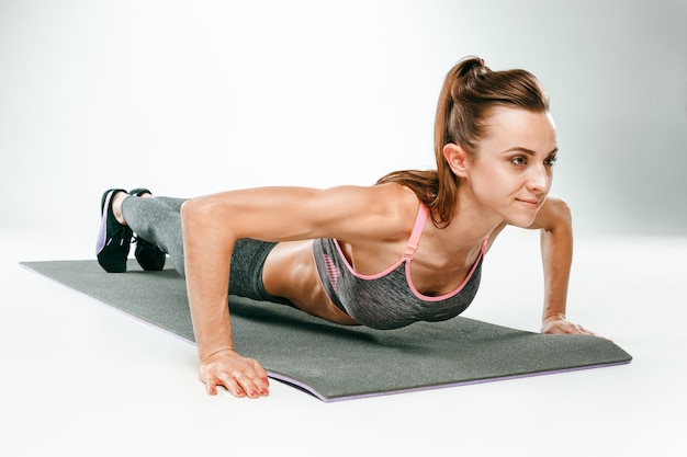 Hermosa morena delgada haciendo algunas flexiones en el gimnasio