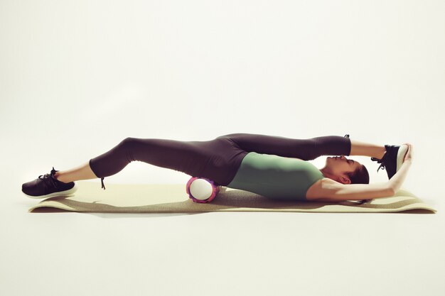 Hermosa morena delgada haciendo algunos ejercicios de estiramiento en un gimnasio