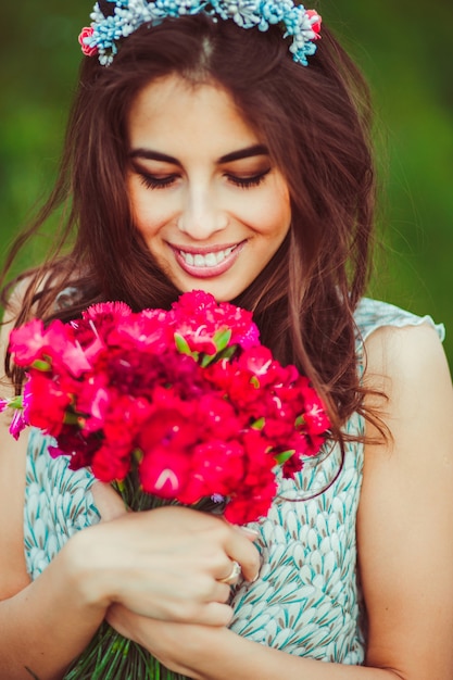 Hermosa morena con flores rojas en sus brazos