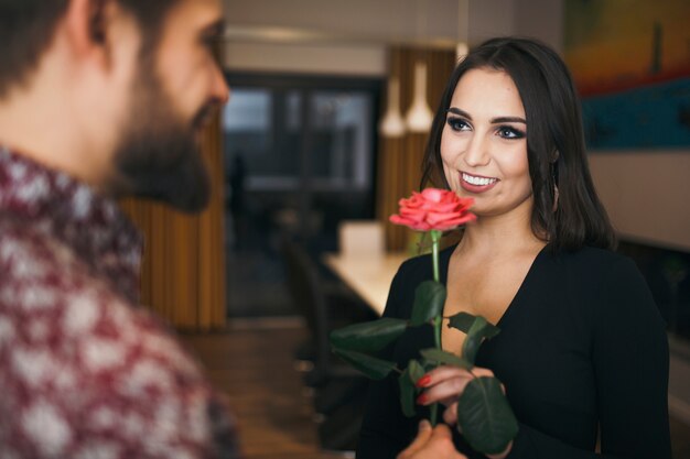 Hermosa morena recibiendo rosa rosa del hombre