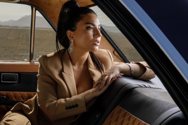 Hermosa morena sentada en un auto y mirando a un lado