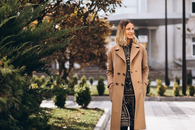 Foto gratuita hermosa mujer en un abrigo beige afuera en el parque