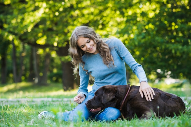 Hermosa mujer acariciando a su perro en el jardín