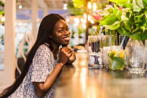 Hermosa mujer africana bebiendo limonada sentado en la cafetería.