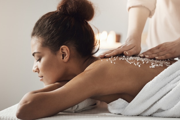 Hermosa mujer africana descansando disfrutando de masaje de salud spa con sal marina.