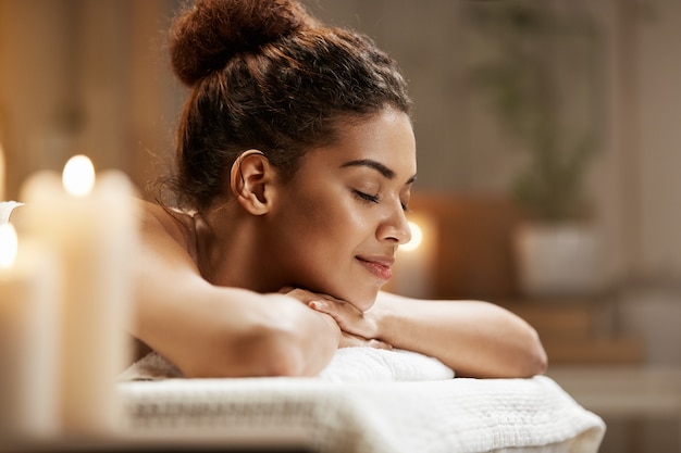 Hermosa mujer africana descansando relajante en balneario con los ojos cerrados.