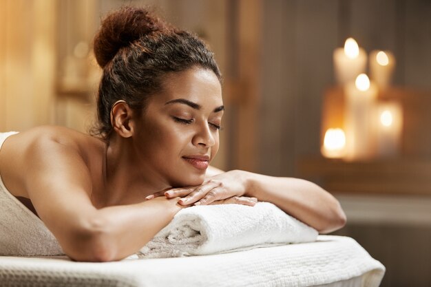 Hermosa mujer africana descansando relajante en balneario con los ojos cerrados.