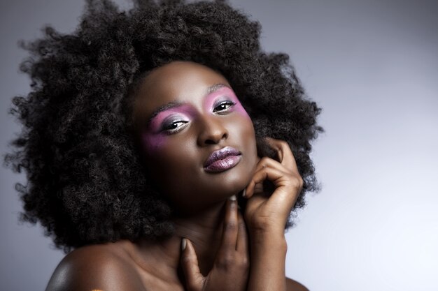 Hermosa mujer africana con gran afro rizado y flores en el pelo