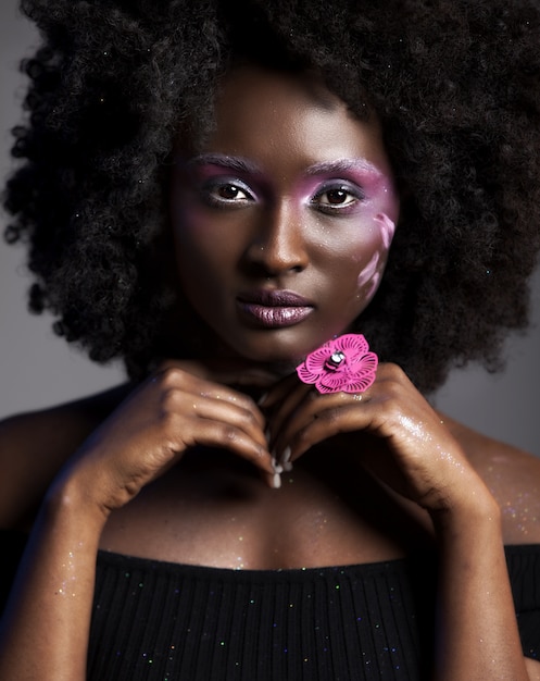 Foto gratuita hermosa mujer africana con gran afro rizado y flores en el pelo