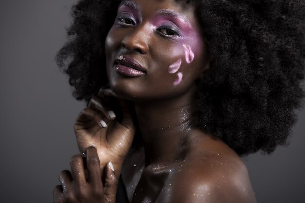 Hermosa mujer africana con gran afro rizado y flores en el pelo