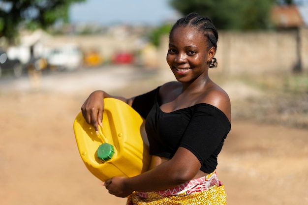 Hermosa mujer africana sosteniendo un recipiente de agua amarillo