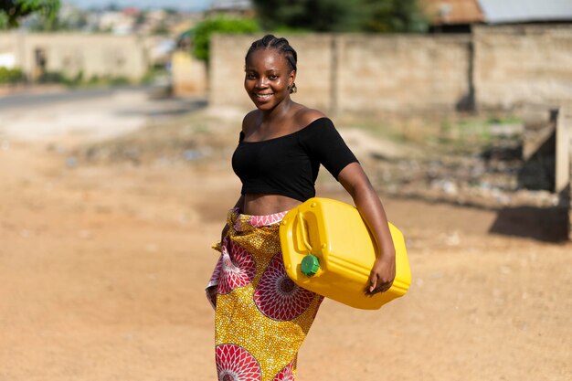 Hermosa mujer africana sosteniendo un recipiente de agua