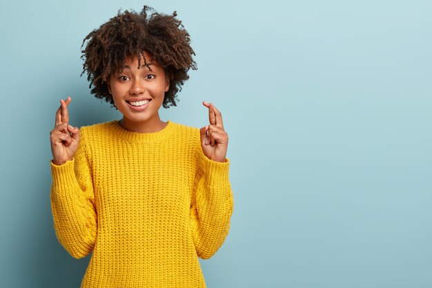 Hermosa mujer con un afro posando en un suéter rosa