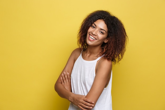 Hermosa mujer afroamericana atractiva con gafas de moda publicar sobre fondo de estudio amarillo. Espacio De La Copia.