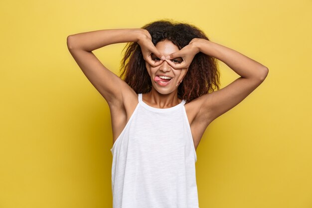 Hermosa mujer afroamericana atractiva con gafas de moda publicar sobre fondo de estudio amarillo. Espacio De La Copia.