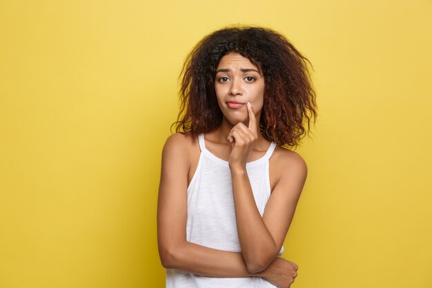 Hermosa mujer afroamericana atractiva con gafas de moda publicar sobre fondo de estudio amarillo. Espacio De La Copia.