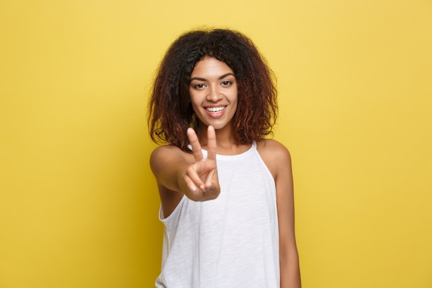 Hermosa mujer afroamericana atractiva con gafas de moda publicar sobre fondo de estudio amarillo. Espacio De La Copia.