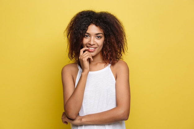 Hermosa mujer afroamericana atractiva con gafas de moda publicar sobre fondo de estudio amarillo. Espacio De La Copia.