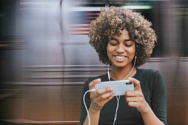 Hermosa mujer afroamericana con smartphone en el metro remezclado medios