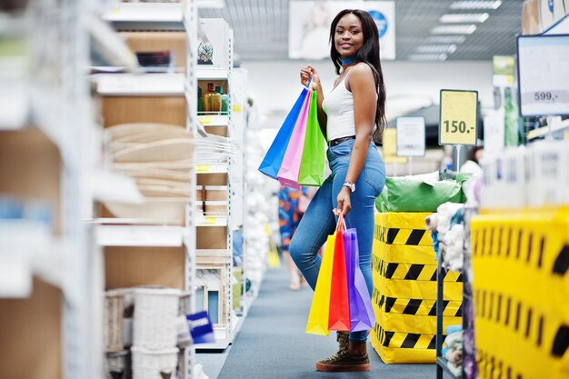 Hermosa mujer afroamericana sosteniendo bolsas de compras multicolores en una tienda