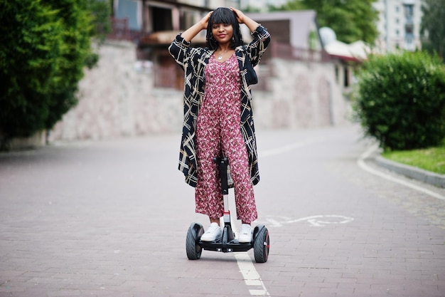 Hermosa mujer afroamericana usando segway o hoverboard Niña negra en scooter eléctrico autoequilibrado de doble rueda