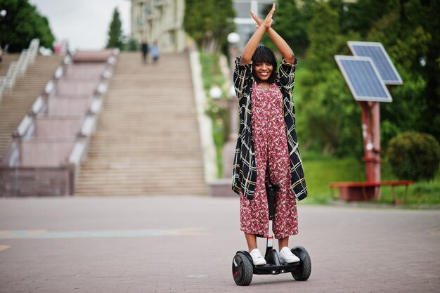 Hermosa mujer afroamericana usando segway o hoverboard Niña negra en scooter eléctrico autoequilibrado de doble rueda