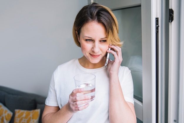 Foto gratuita hermosa mujer con agua hablando por teléfono