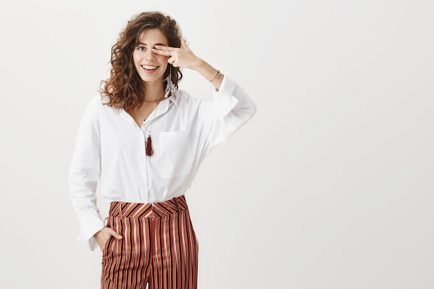 Hermosa mujer alegre cubre un ojo, sonriendo