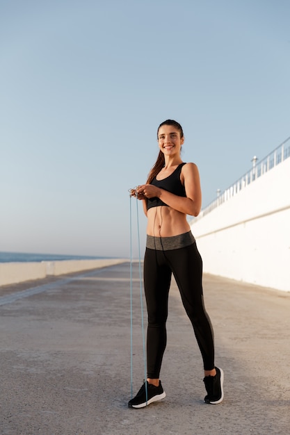 Hermosa mujer alegre con saltar la cuerda entrenamiento aislado