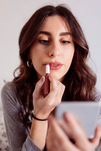 Hermosa mujer aplicando lápiz labial