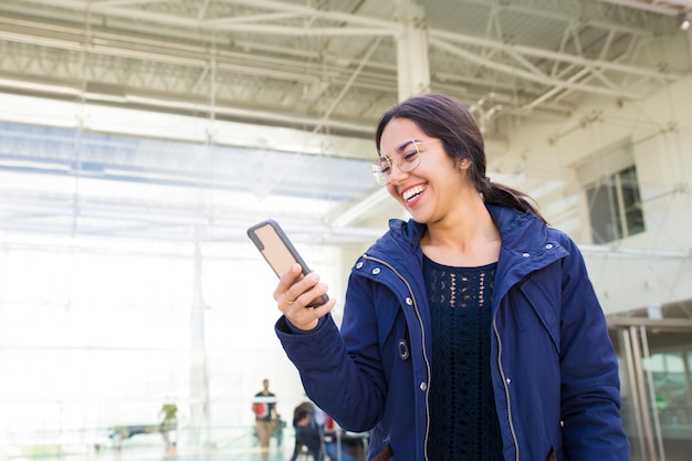 Hermosa mujer asiática en anteojos mirando smartphone