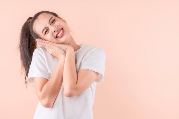 Hermosa mujer asiática atractiva Sonriendo con las manos entrelazadas Señora mirando a la cámara Concepto de ternura Vista frontal aislada sobre fondo de color