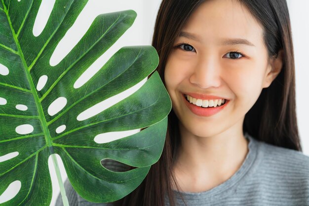 Hermosa mujer asiática de camisa blanca disfruta jugando con el concepto de ides veganas de vegetales de hoja verde en el estilo de vida de vacaciones de cama blanca