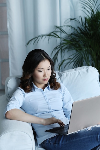 Hermosa mujer asiática en casa con laptop