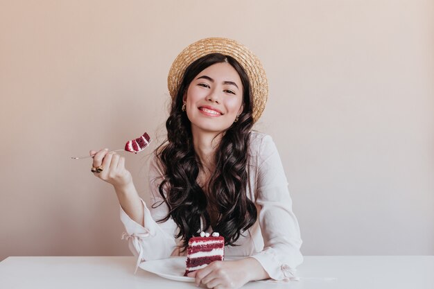 Hermosa mujer asiática comiendo pastel. Mujer de cumpleaños sonriente disfrutando de postre.