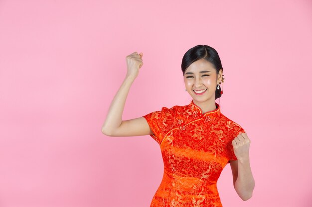 Hermosa mujer asiática feliz sonríe y se siente emocionada en año nuevo chino sobre fondo rosa.