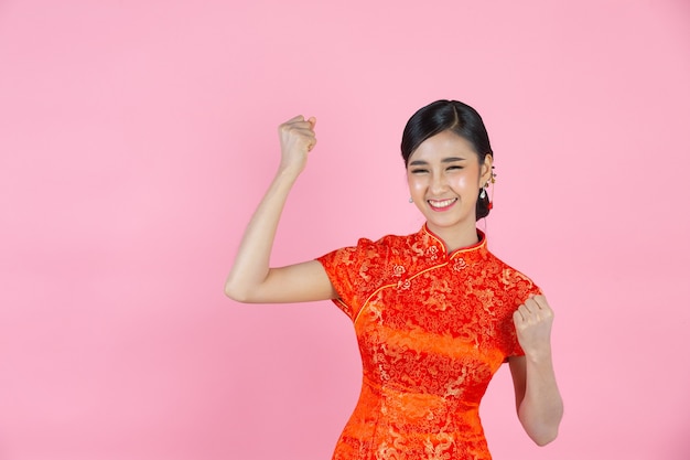 Hermosa mujer asiática feliz sonríe y se siente emocionada en año nuevo chino sobre fondo rosa.