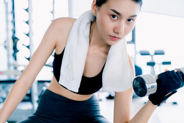 Hermosa mujer asiática en forma haciendo ejercicio con Dumbbell Bicep Curls concepto de ideas saludables en el gimnasio fitness