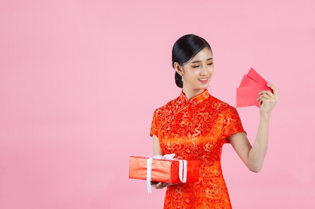 Hermosa mujer asiática muestra algo y toma sobres rojos en año nuevo chino