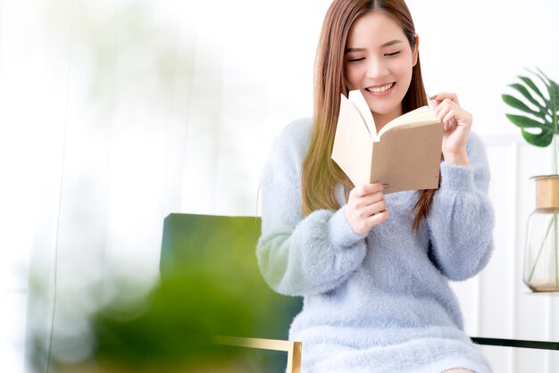 Hermosa mujer asiática de pelo largo disfruta del momento del fin de semana con el fondo de la habitación blanca del libro