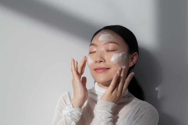 Hermosa mujer asiática posando con crema facial