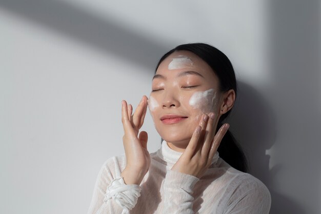 Hermosa mujer asiática posando con crema facial