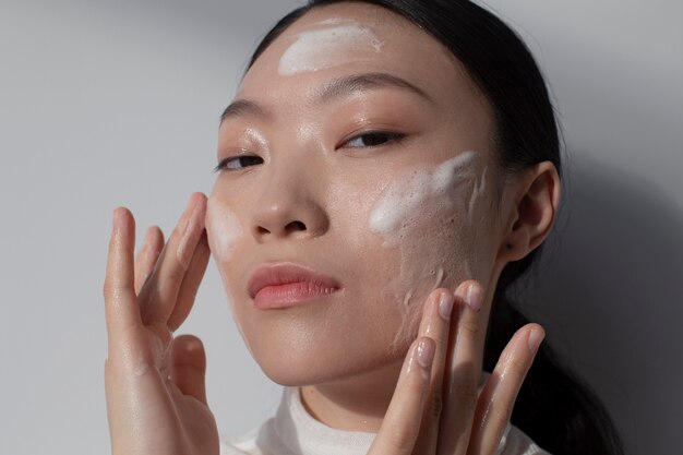 Hermosa mujer asiática posando con crema facial