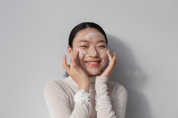 Hermosa mujer asiática posando con crema facial