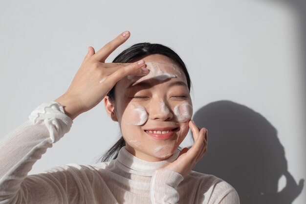 Hermosa mujer asiática posando con crema facial