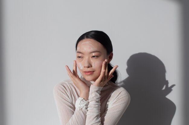 Hermosa mujer asiática posando con crema facial