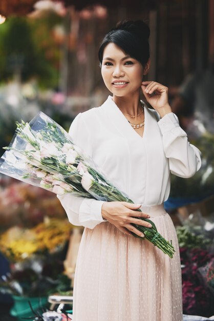 Hermosa mujer asiática posando con gran ramo en florería