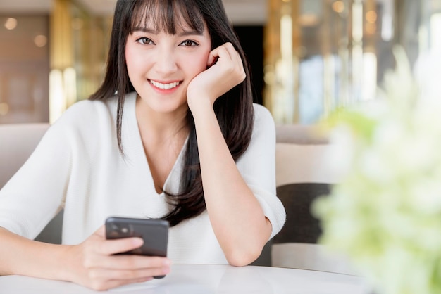 Hermosa mujer asiática retrato de pelo largo y negro suéter blanco con sonrisa de felicidad y pensamiento positivo